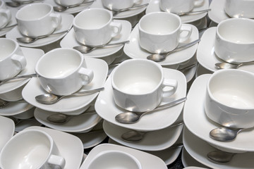 Smooth rows of white tea cups with spoons on a table in a restaurant