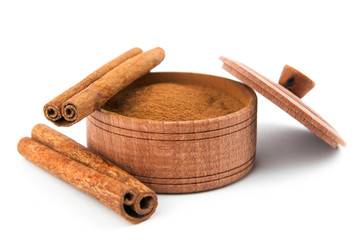 Cinnamon sticks and cinnamon powder in a wooden bowl.