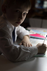 Boy  with pencil writing english words by hand on traditional white notepad paper.