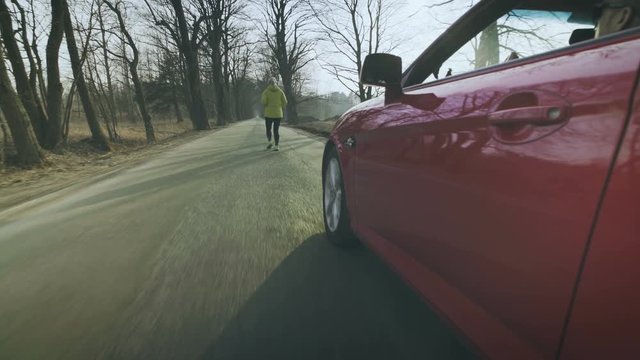The driver of the car drives alongside the running girl and slaps her butt.