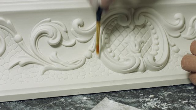 Worker cleaning gypsum ornament close up. Man working with ornament of gypsum construction. Stucco molding concept. Beauty of classical architecture. Restoration of baroque style building.