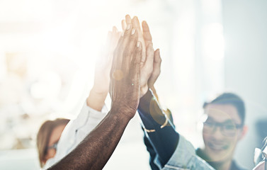 Diverse team of businesspeople high fiving together in an office