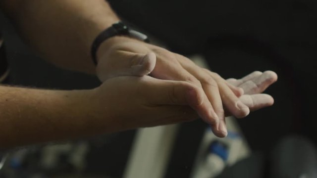 a man rubs his hands with talcum in the gym