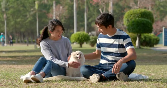 Young couple with Pomeranian dog at outdoor park