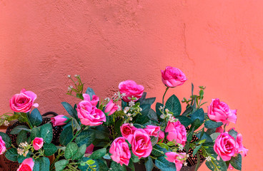 Pink artificial Flowers on orange wall in resort, Thailand.