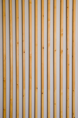 Wooden vertical slats batten on a light gray wall background. Interior detail, texture, background. The concept of minimalism and Scandinavian style in the interior. Copy space