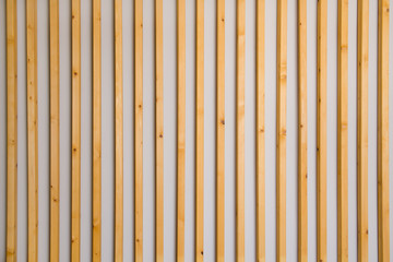 Wooden vertical slats batten on a light gray wall background. Interior detail, texture, background. The concept of minimalism and Scandinavian style in the interior. Copy space - obrazy, fototapety, plakaty