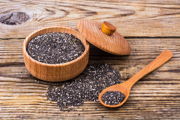 Heap of chia seeds in bowl on grey wooden table