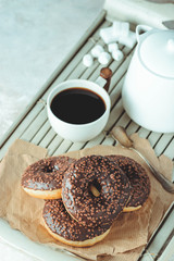 Chocolate donuts and coffee , weekend morning table. Breakfast on a wooden tray. Vintage colors.