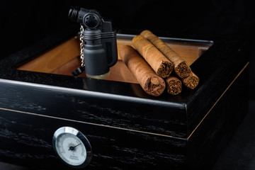 Cigars on a humidor against a black background