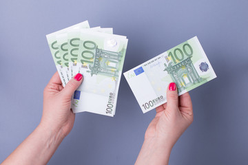 Hands of a woman holding EURO banknotes on a blue background. Saving for the future life