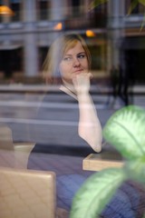 Portrait of attractive redhead plus size woman sitting in cafe, photo throught the glass