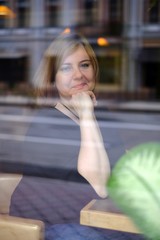 Portrait of attractive redhead plus size woman sitting in cafe, photo throught the glass