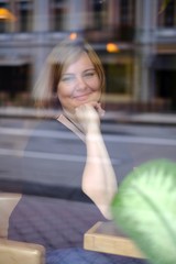 Portrait of attractive redhead plus size woman sitting in cafe, photo throught the glass
