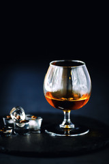 a glass of cognac on a black background, apperetiv with ice and coffee beans