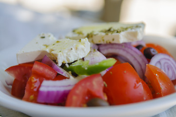 Greek Salad made up of tomatoes, cucumber, olives, red onions, feta cheese and fresh herbs