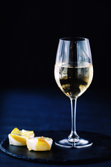 a glass of white wine on a black table with a fruit dessert