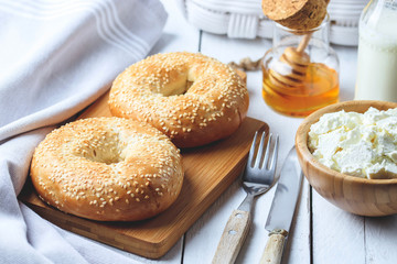 Bagel with cottage cheese , banana and honey. Concept of healthy breakfast. White wooden background.