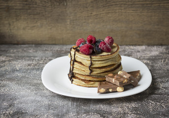 панкейки посыпанные ягодами и кусочками шоколада лежат на тарелке