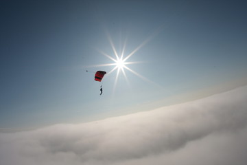 skydiver flying in the background of blue sky and sun