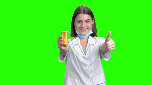 Female doctor advertise orange can of pills. Green screen hromakey background for keying.