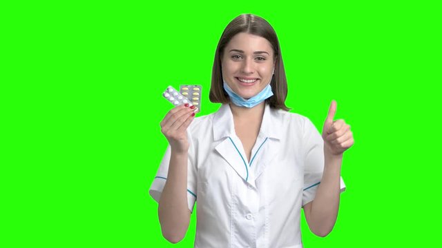 Packs of pills advertisement. Portrait of young beautiful cute brenette woman recomemnding and selling pills. Green screen hromakey background for keying.
