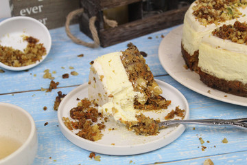 A piece of Carrot Cake Cheesecake with Sour Cream Topping on a white plate, blue background