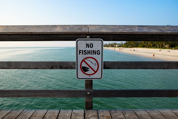 No Fishing Sign on Wooden Pier Against Sea and Beach