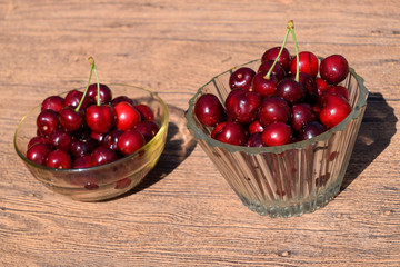 Berries of a sweet cherry in a glass bowl on a wooden background. Ripe red sweet cherry