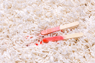 Red Popsicle melting on carpet