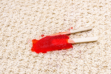 Red Popsicle melting on carpet