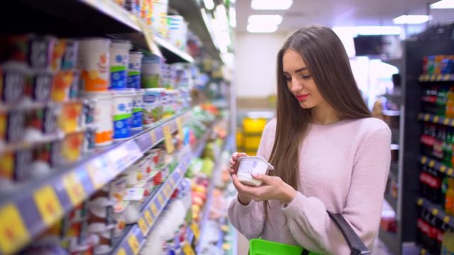Woman chooses yogurt at a supermarket. 4 k