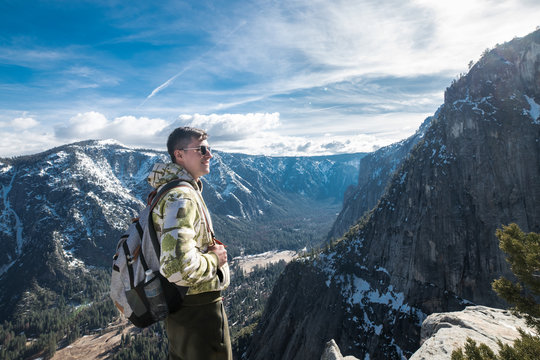 Tourist man with backpack enoy the view on mountain top in Yosemite National Park