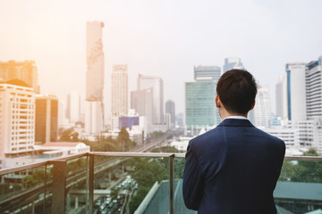 Fototapeta na wymiar Businessman in blue suit looking at city view in Bangkok city, Thailand