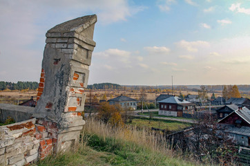 Fototapeta na wymiar The falling wall against the background of the Russian rural landscape