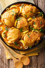 Arabian food: braised chicken with lemons, onions, spices and green olives close-up. Vertical top view