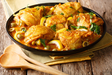 Arabian food: braised chicken with lemons, onions, spices and green olives close-up on a plate on a table. horizontal