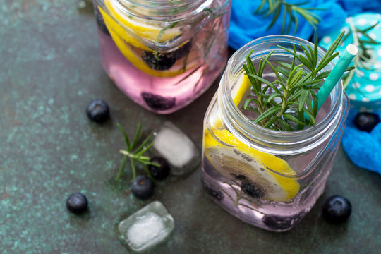 Mason jar mugs with homemade refreshing drink with blueberries and rosemary close-up. Diet, concept of vegetarian food. Proper nutrition. Copy space.