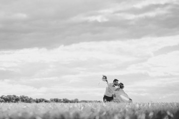 Married couple running in a field, having fun and smiling. She is looking back.