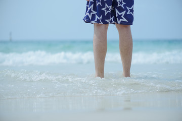 Beach travel - woman walking on sand beach leaving footprints in the sand.