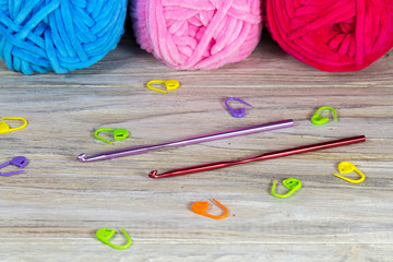 Pastel colored yarn on the wooden table crochet hooks