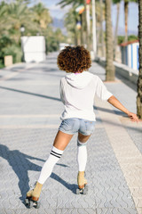 Black woman on roller skates rollerblading in beach promenade with palm trees