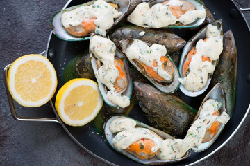 Above view of baked kiwi mussels with cheese sauce and lemon, horizontal shot, closeup