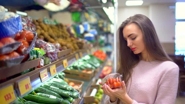 woman in a supermarket selects the tomatoes choosing vegetables in supermarket. 4 k