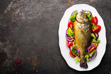 Baked fish dorado. Dorado fish oven baked and fresh vegetable salad on plate. Sea bream or dorada...
