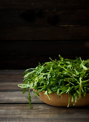 Fresh rucola with water droplets on a dark rustic background