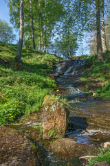 Stream and a waterfall in a ravine at summer