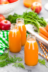 Fresh carrot and apple juice on white background. Carrot and apple juice in glass bottles on white table. Apple and carrot juice on white background