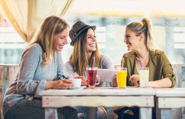 Group of female friends in cafe using digital tablet