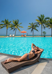 Fototapeta na wymiar Woman at the swimming pool at the tropical resort